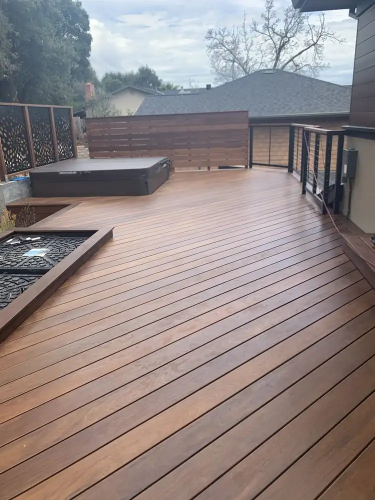Brown deck with a privacy screen and black railing