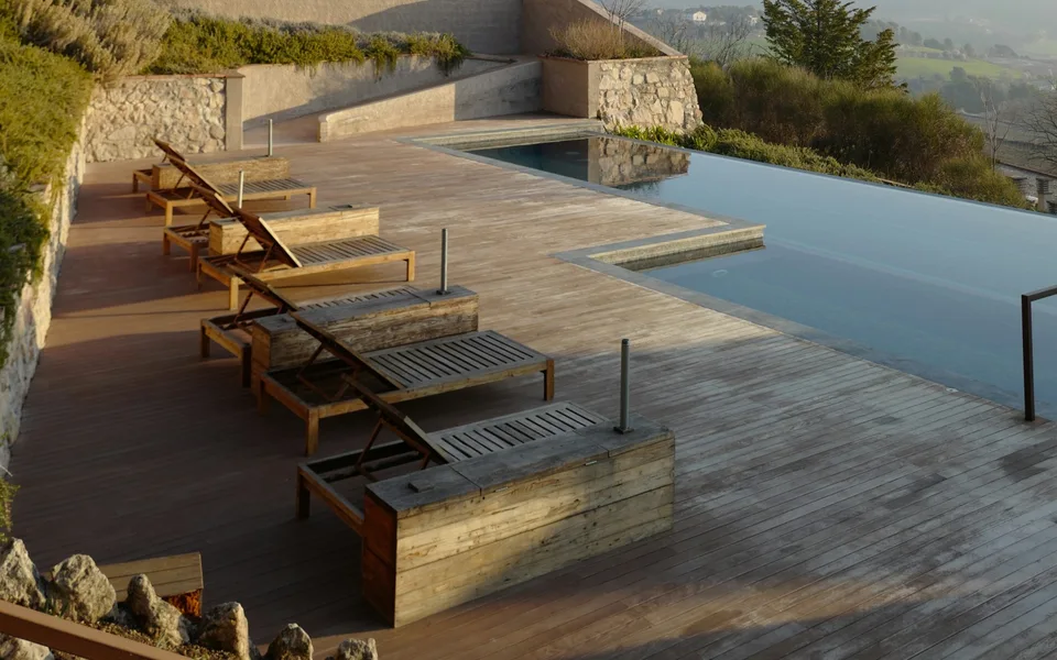 Wooden lounge chairs on a wood deck beside an outdoor pool
